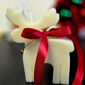 Kerst cadeauset met witte figuurkaarsen: rendier, kerstboom en gingerbread in gouden doos met rood lint en gouden belletjes